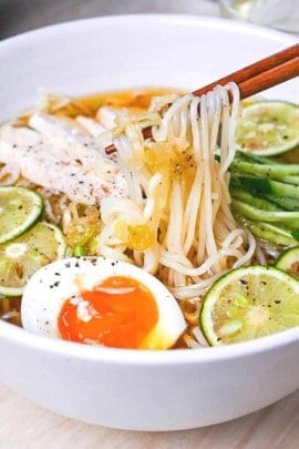 Chicken and citrus somen noodle soup in a white bowl with slices of sudachi