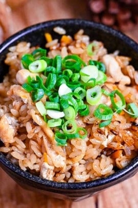 chicken takikomi gohan in a black rice bowl topped with chopped green onion