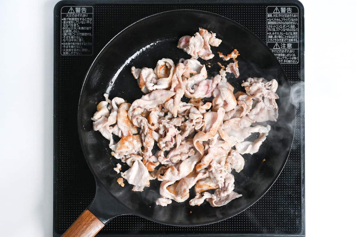 thinly sliced pork frying in a pan