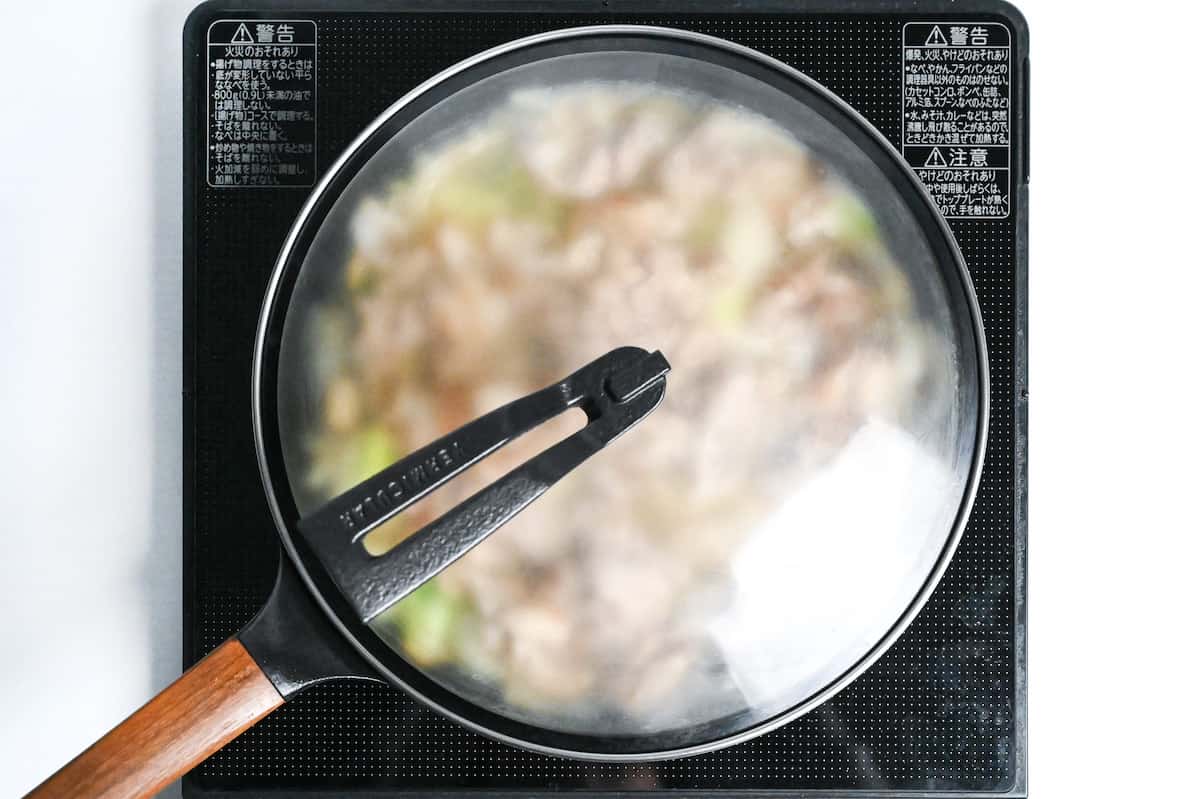 steaming egg in pan with pork and vegetables using lid on frying pan