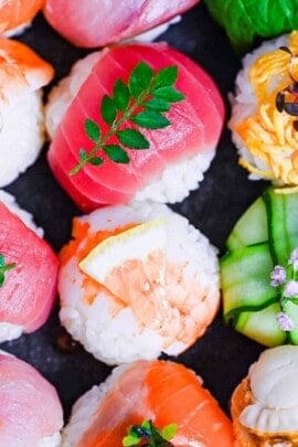 decorative temarizushi made with various seafood, eggs and vegetables topped with leaves, salmon roe, flowers and lemon slices