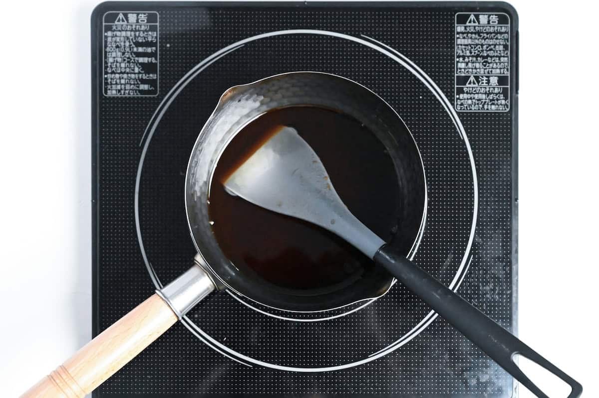 homemade tendon sauce in a saucepan on the stove with silicone spatula