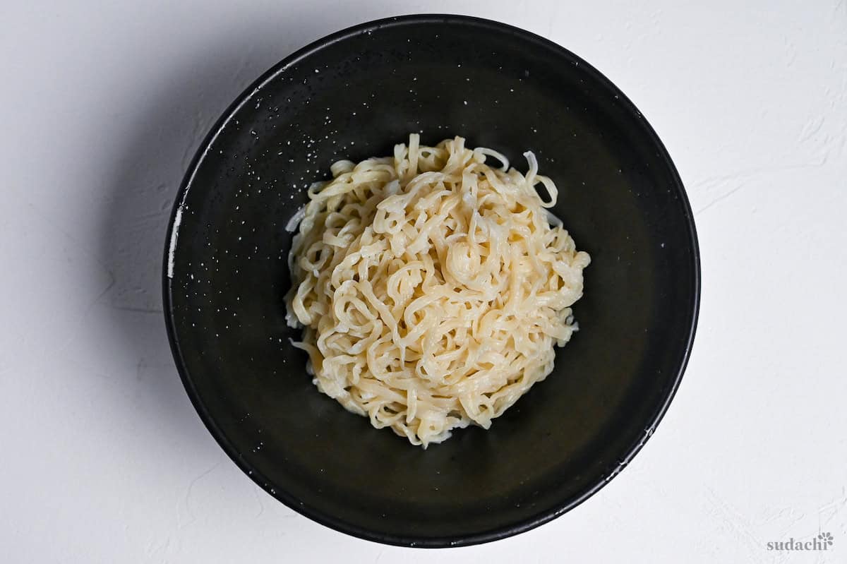 cooked ramen noodles in a black ramen bowl on a white background