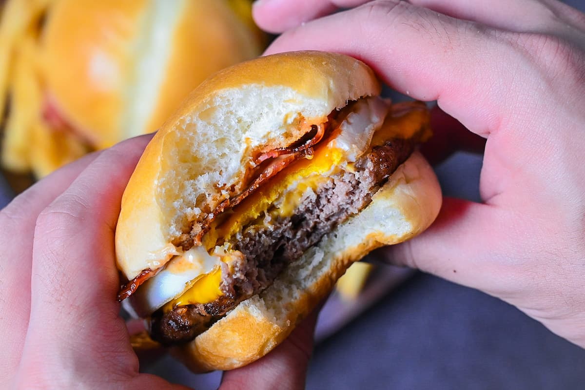 Japanese tsukimi burger on a brown rectangular plate with fries
