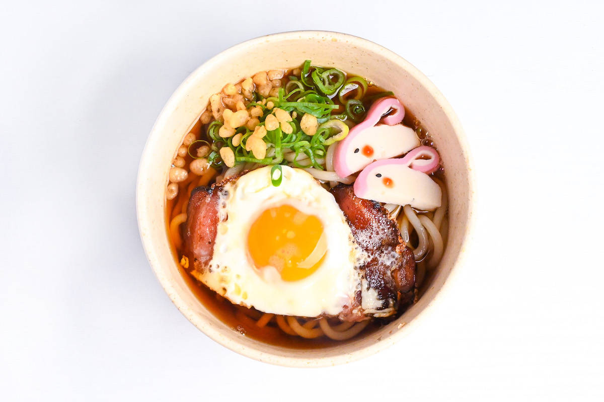 tsukimi udon topped with bacon, fried egg, green onions, tenkasu and rabbit shaped kamaboko fish cakes