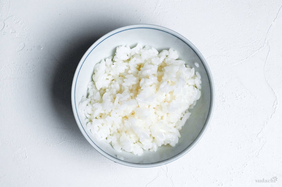 washed and cooled cooked rice in a white bowl with blue rim