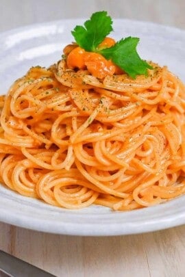 Japanese uni cream pasta served on a white plate and topped with black pepper and parsley