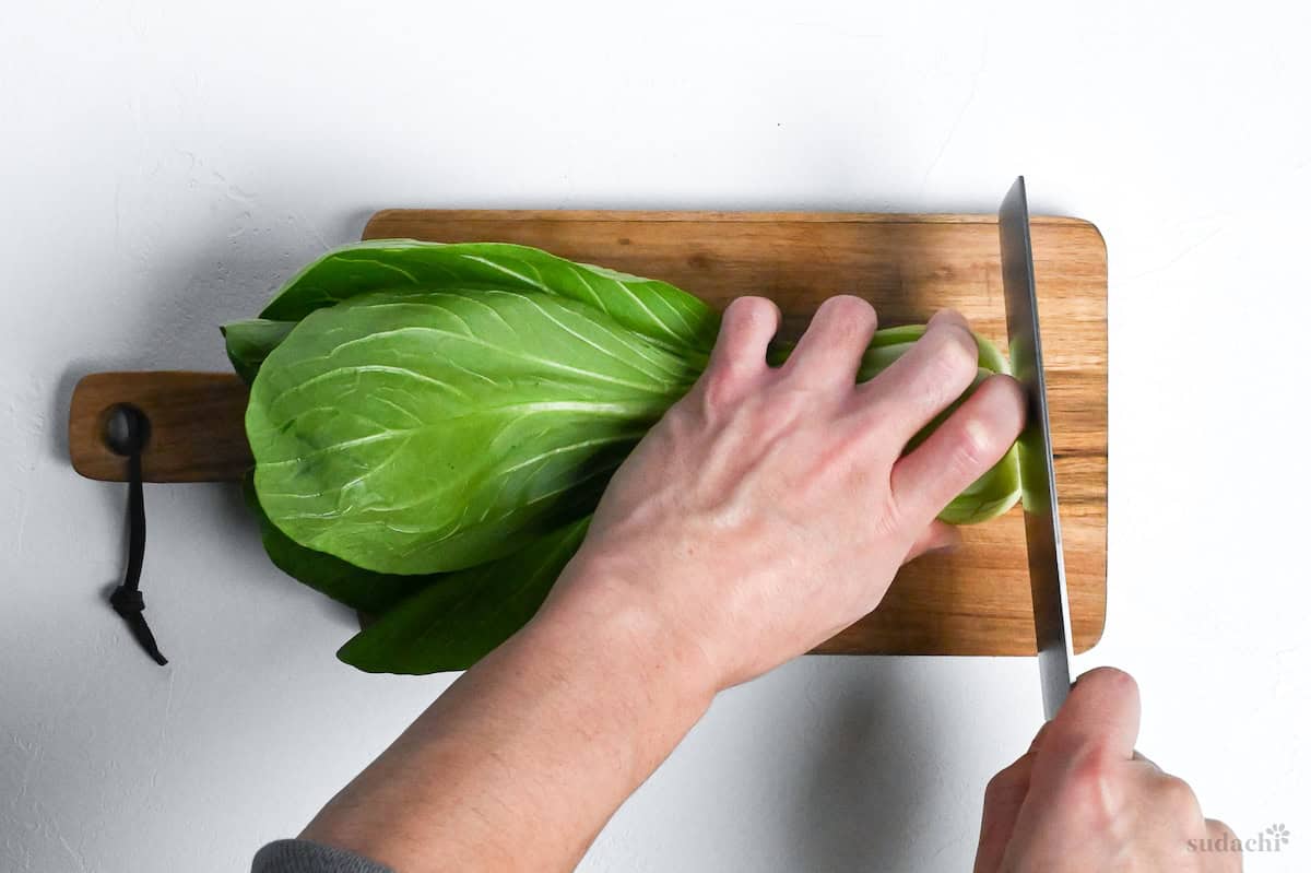 cutting the end of bok choy on a wooden chopping board