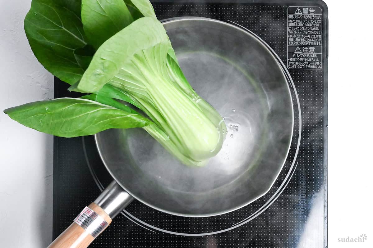 the stems of bok choi in a pot of boiling water
