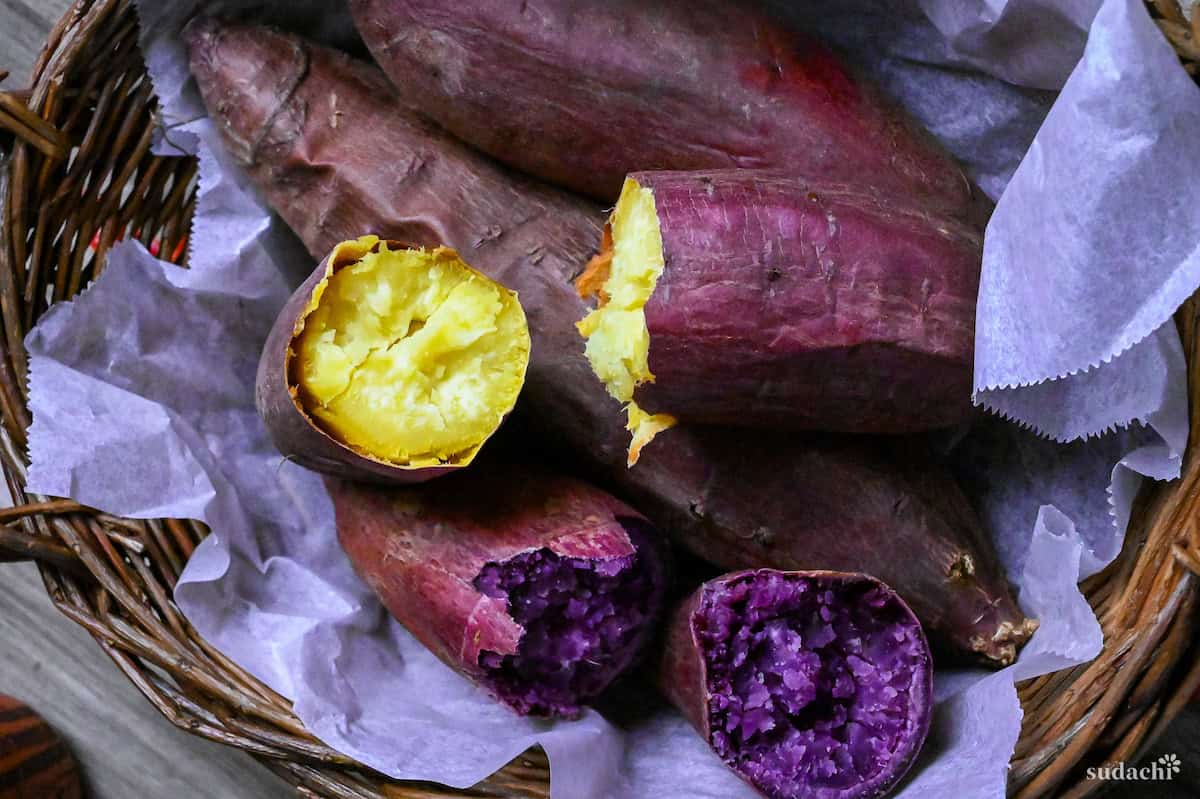 Yaki imo (baked Japanese sweet potatoes) in a woven basket lined with paper and surrounded by pinecones and maple leaves