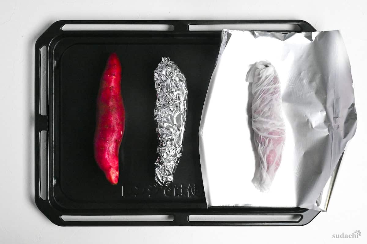 Three Japanese sweet potatoes on a baking tray. One unwrapped, one wrapped with foil and one wrapped with damp kitchen paper and foil