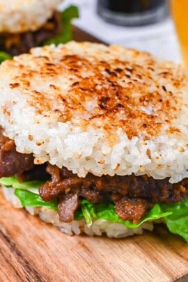 Yakiniku Rice Burger filled with frilly lettuce and yakiniku style pan fried beef on a wooden chopping board
