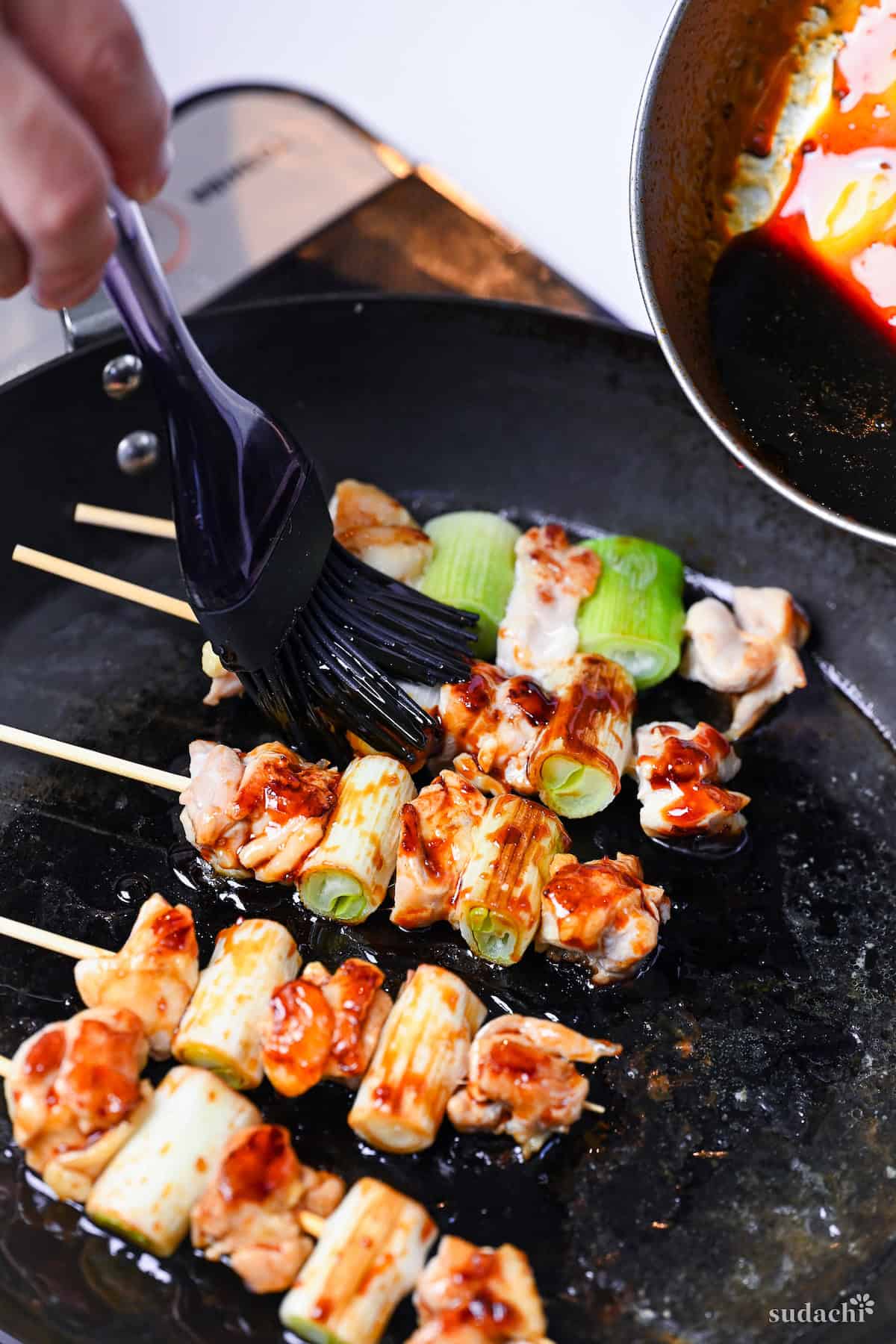 brushing pan-fried yakitori with homemade sauce