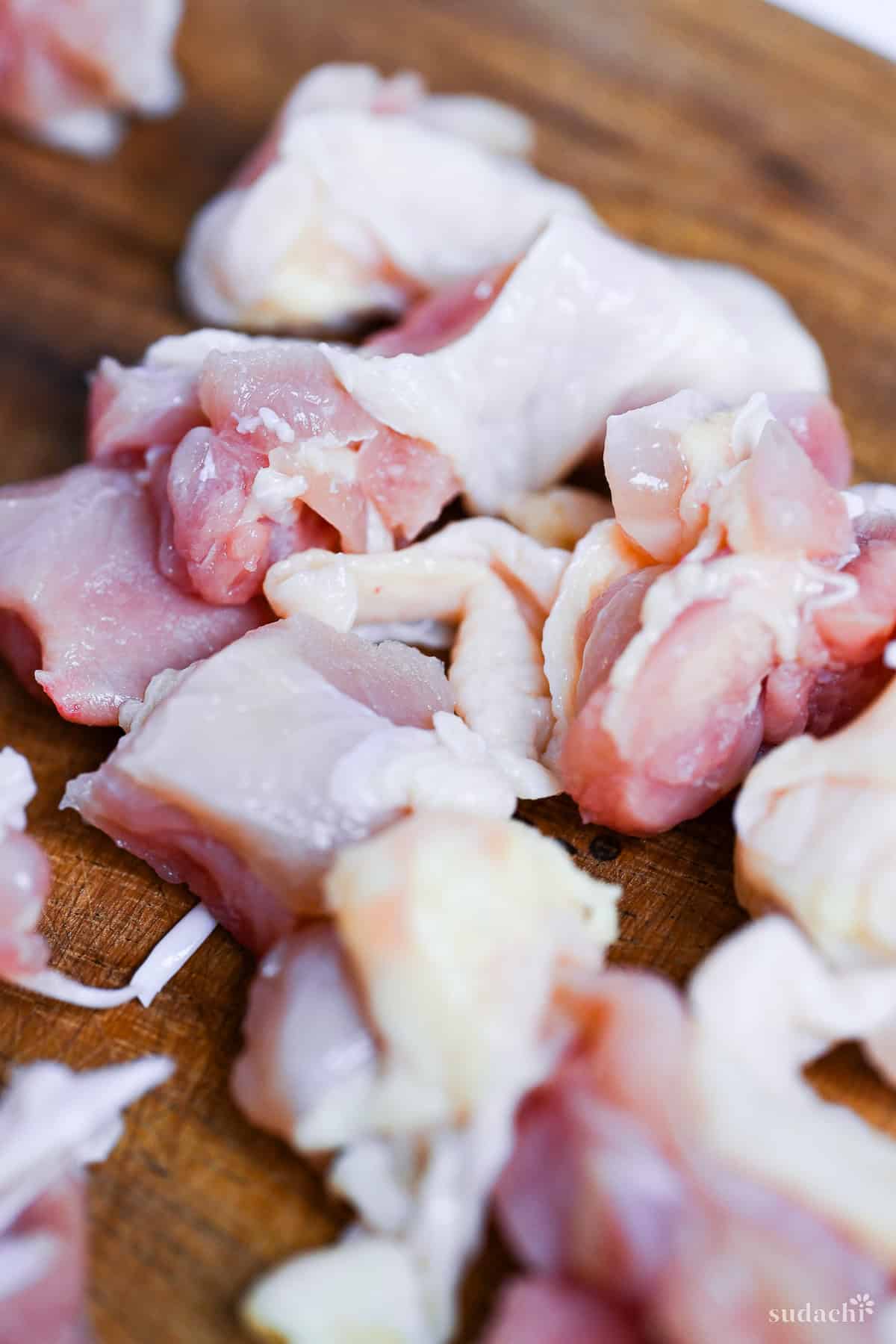 close up of bitesize pieces of chicken thigh on a wooden chopping board