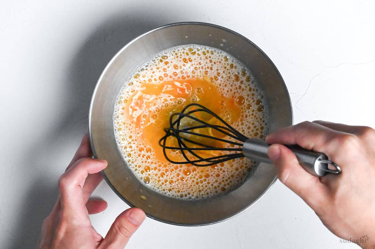 whisking egg yolk and chilled water in a bowl to make tempura batter