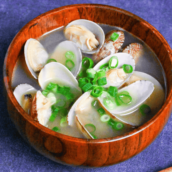 Asari clam miso soup in a wooden bowl on a dark gray background