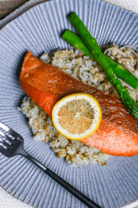 Butter Soy Sauce Salmon (Japanese-Style Salmon Meunière) on a bed of garlic rice next to sautéed asparagus and enoki mushrooms on a blue striped dinner plate top down