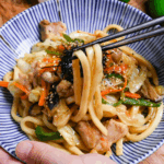 holding chicken butter shoyu yaki udon with chopsticks