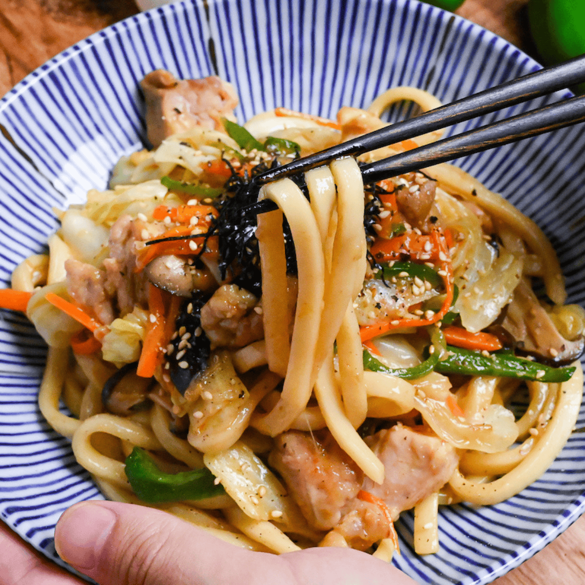 holding chicken butter shoyu yaki udon with chopsticks