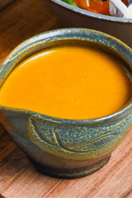 Japanese carrot salad dressing in a small green ceramic jug on a wooden board close up