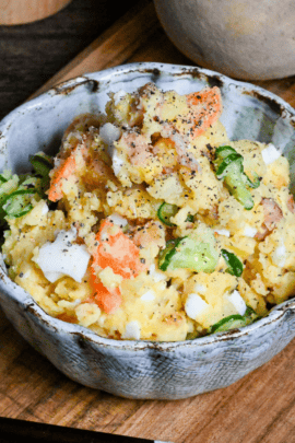 Japanese izakaya style potato salad in a light blue bowl on a wooden board