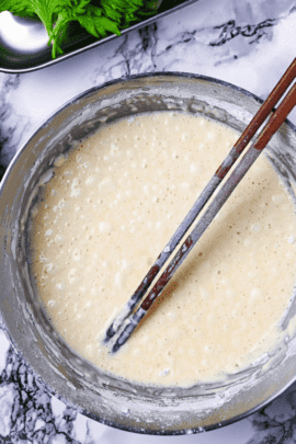 tempura batter in a mixing bowl with wooden chopsticks