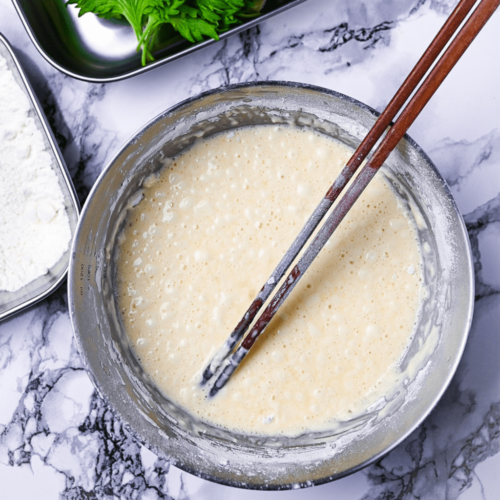 tempura batter in a mixing bowl with wooden chopsticks