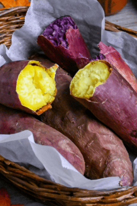 Yaki imo (baked Japanese sweet potatoes) in a woven basket lined with paper and surrounded by pinecones and maple leaves